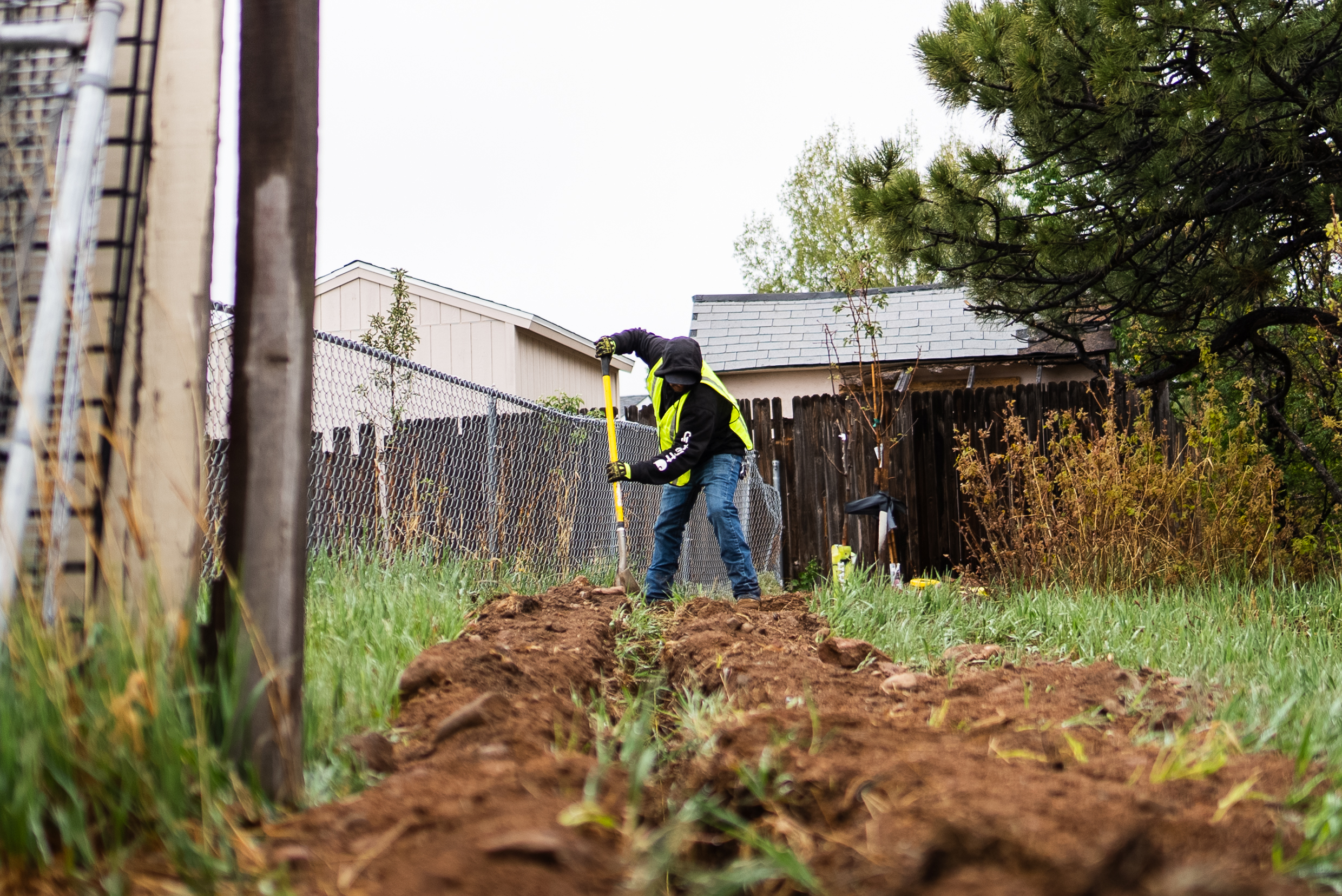 TrenchCore crew member in hi-vis vest digging a residential trench