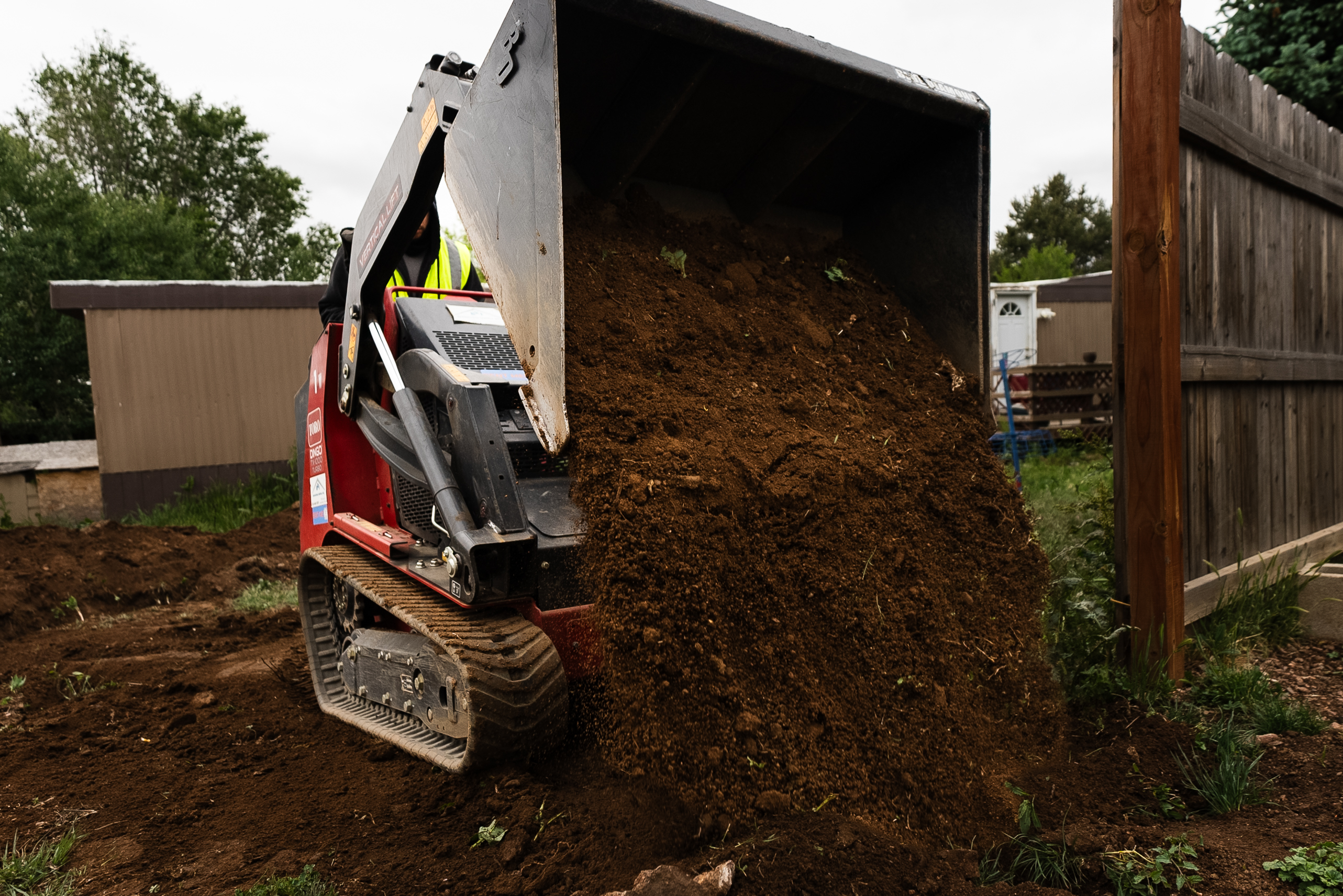 TrenchCore Dingo skid steer dumping excavated soil on an active job site